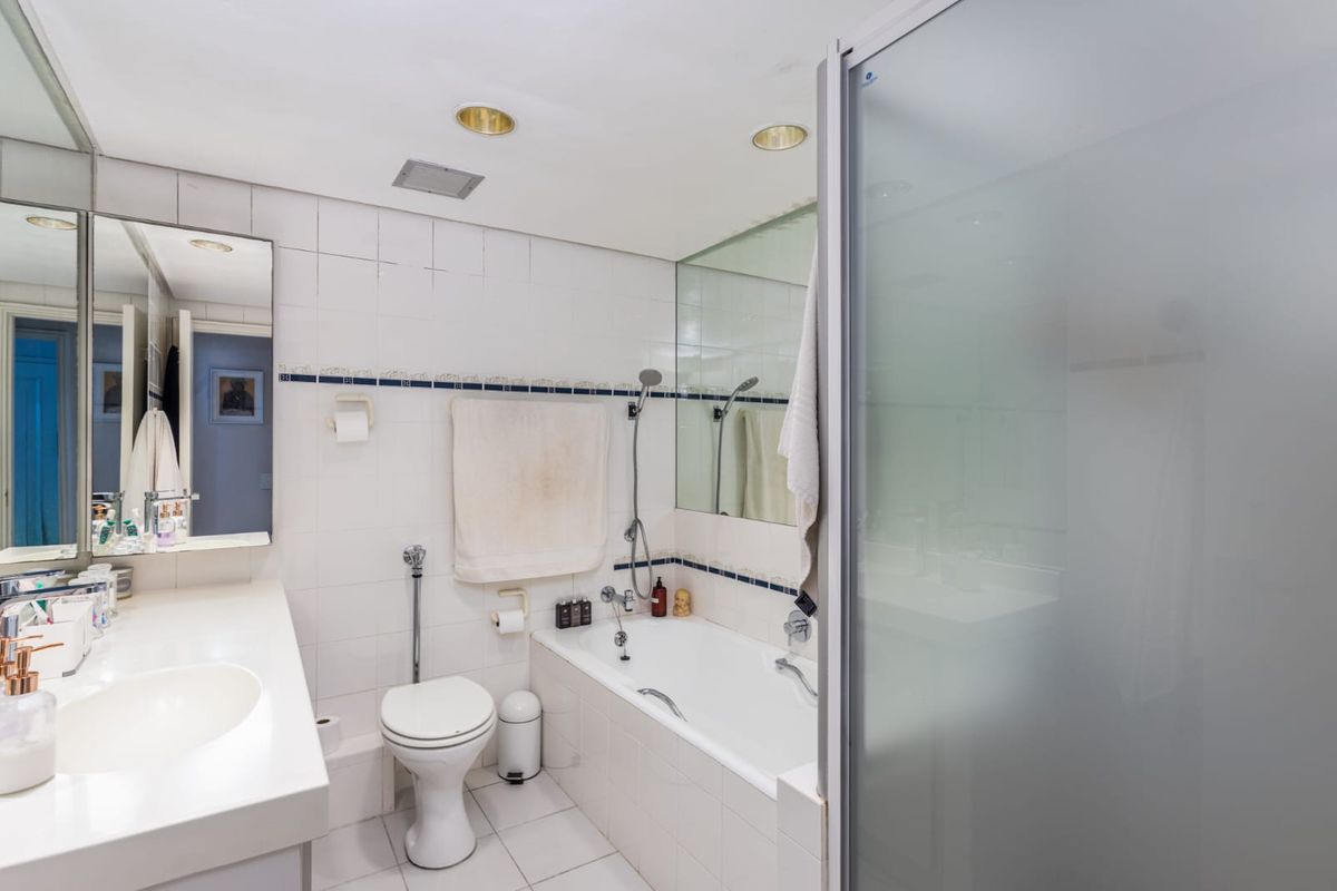 A functional bathroom featuring a built-in vanity with integrated sink, a bathtub with shower attachment, and a separate frosted glass shower enclosure.