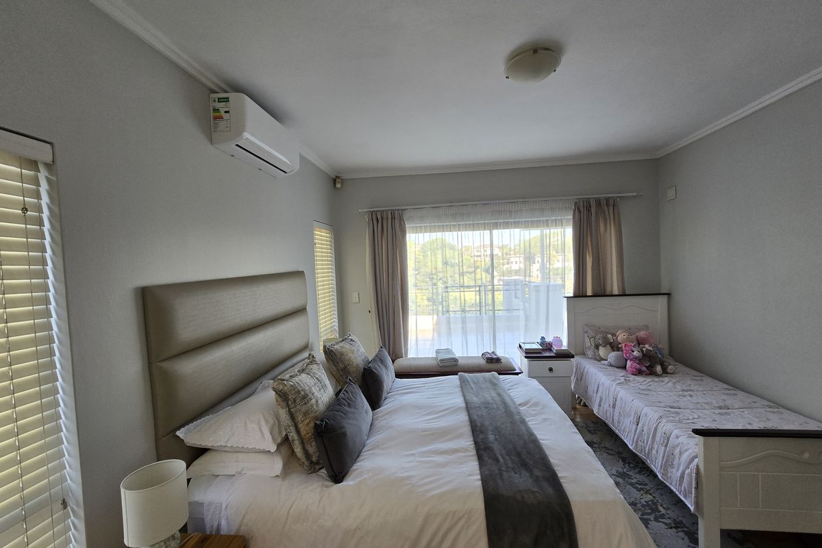 Spacious bedroom featuring a split-system air conditioner, large sliding glass doors leading to a balcony, and neutral wall finishes.