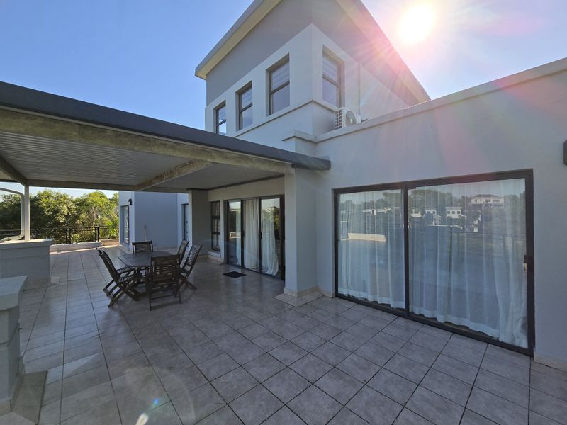 Spacious covered patio featuring tiled flooring, built-in outdoor counter, and large sliding glass doors providing seamless access to the interior living space.