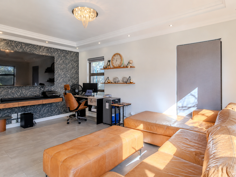 Modern living room featuring a floating media console, feature wallpaper, tiled flooring, and elegant lighting, creating a comfortable and functional space.