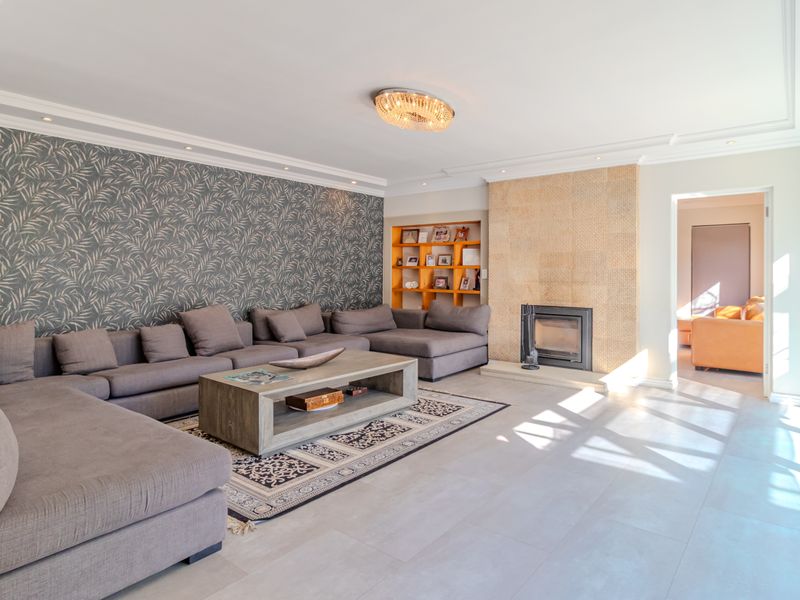 Spacious living room featuring a built-in fireplace, recessed shelving, large sliding glass doors, and modern tiled flooring with elegant cove lighting.