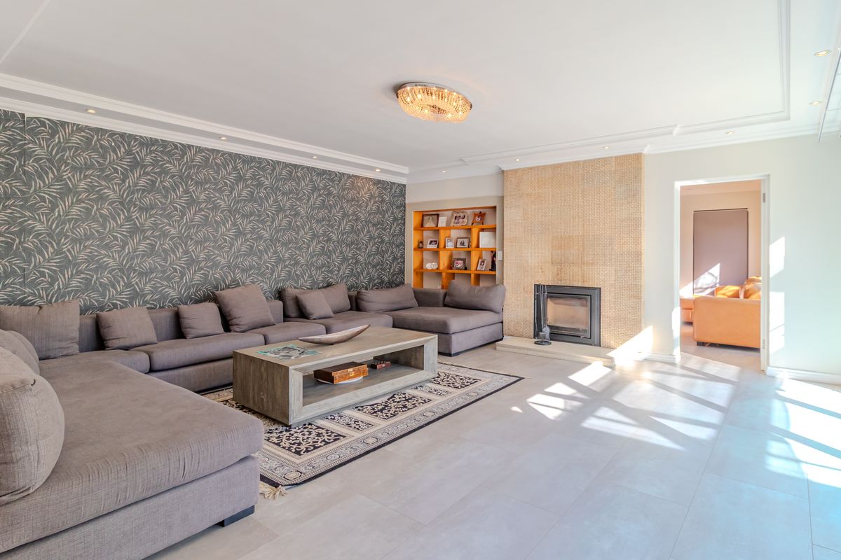 Spacious living room featuring a built-in fireplace, recessed shelving, large sliding glass doors, and modern tiled flooring with elegant cove lighting.