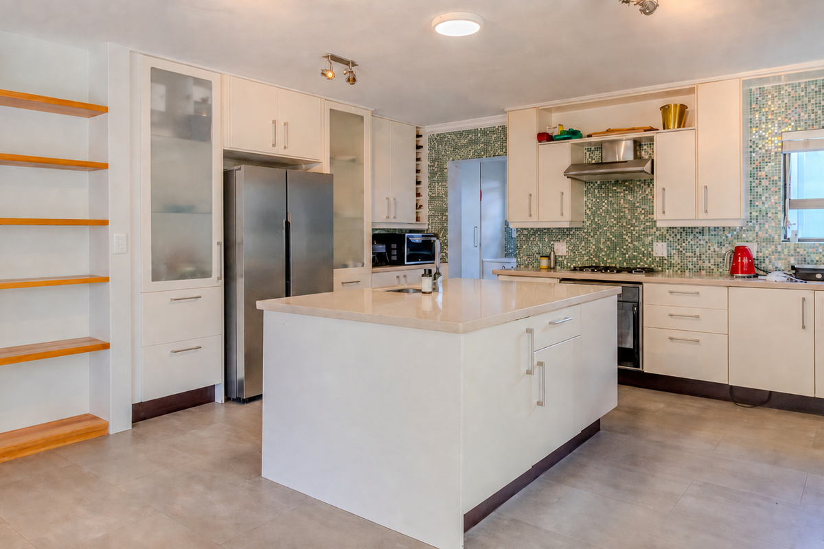 Modern kitchen featuring a central island, stone countertops, ample built-in cabinetry, and a decorative mosaic tile backsplash.