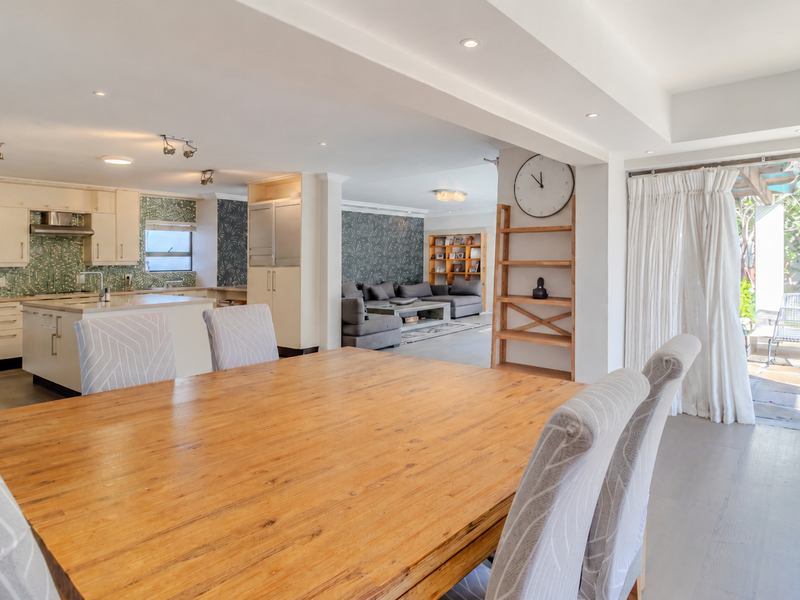 Spacious open-plan living area featuring a modern kitchen with integrated appliances, flowing seamlessly into the dining space and out to the patio.