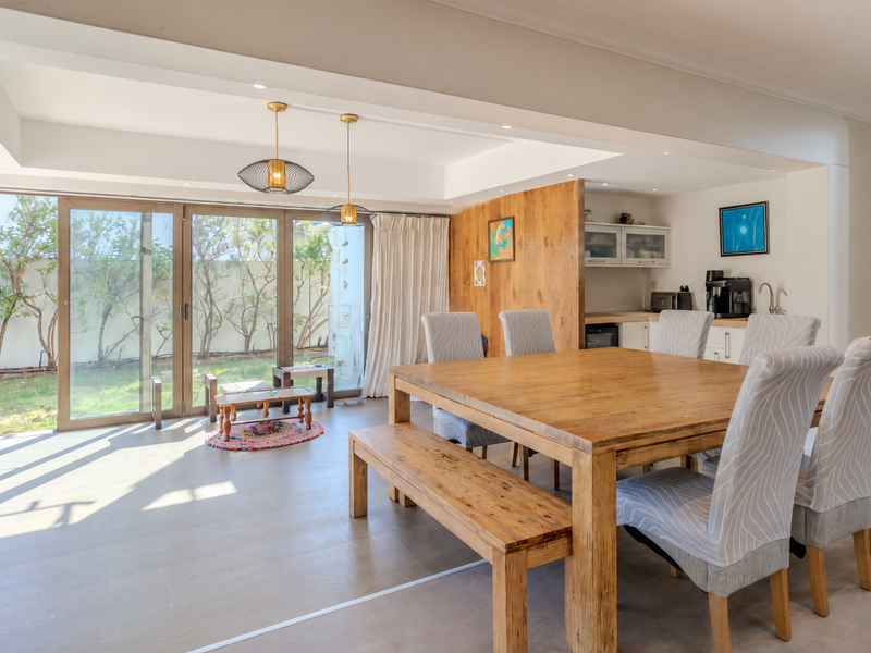 Spacious open-plan dining area featuring timber wall accents, recessed lighting, and large sliding glass doors providing seamless access to the rear garden.