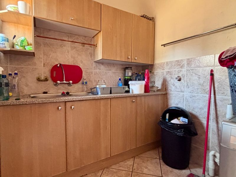 Functional laundry area featuring laminate cabinetry, tiled backsplash, and tiled flooring, providing practical utility space with integrated plumbing connections.