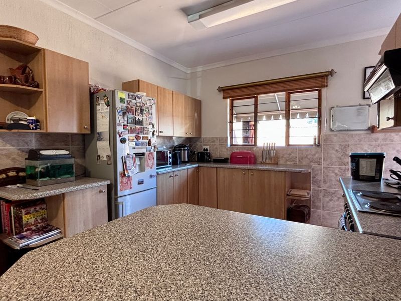 Functional kitchen featuring laminate cabinetry, granite-look countertops, ceramic wall tiling, and built-in cooking appliances with natural light from a window.