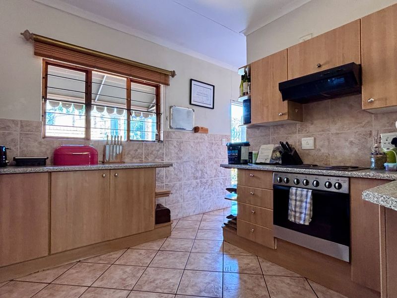 A functional kitchen featuring light wood-finish cabinetry, granite-look laminate countertops, tiled backsplash, and a built-in oven with an extractor fan.