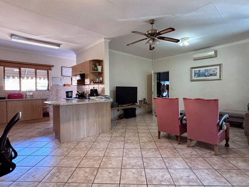 Open-plan living area featuring a kitchen with granite countertops, tiled flooring, and a ceiling fan, creating a functional and connected living space.