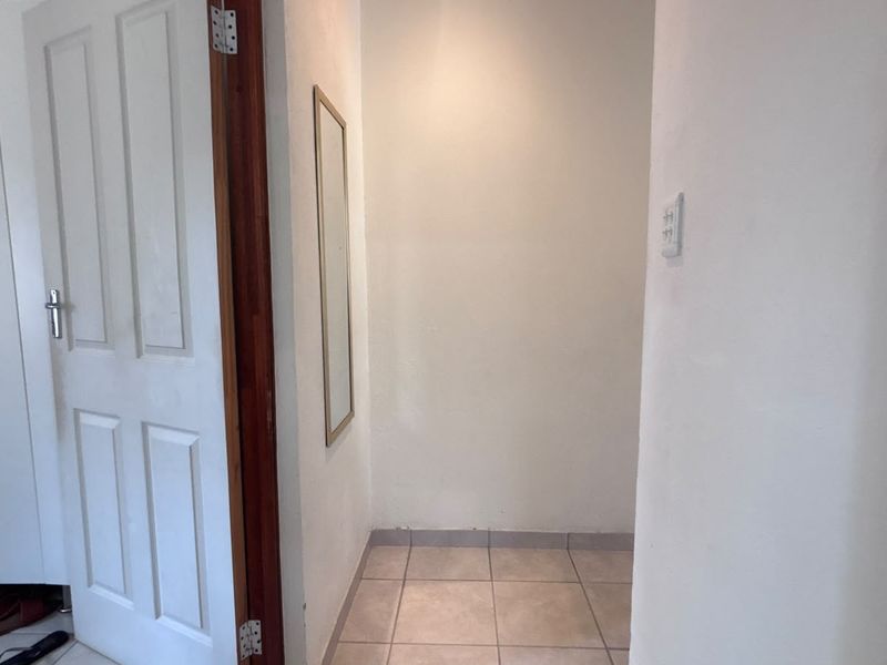 A simple, neutral hallway space featuring tiled flooring and a standard internal door, providing a clean transition between rooms.