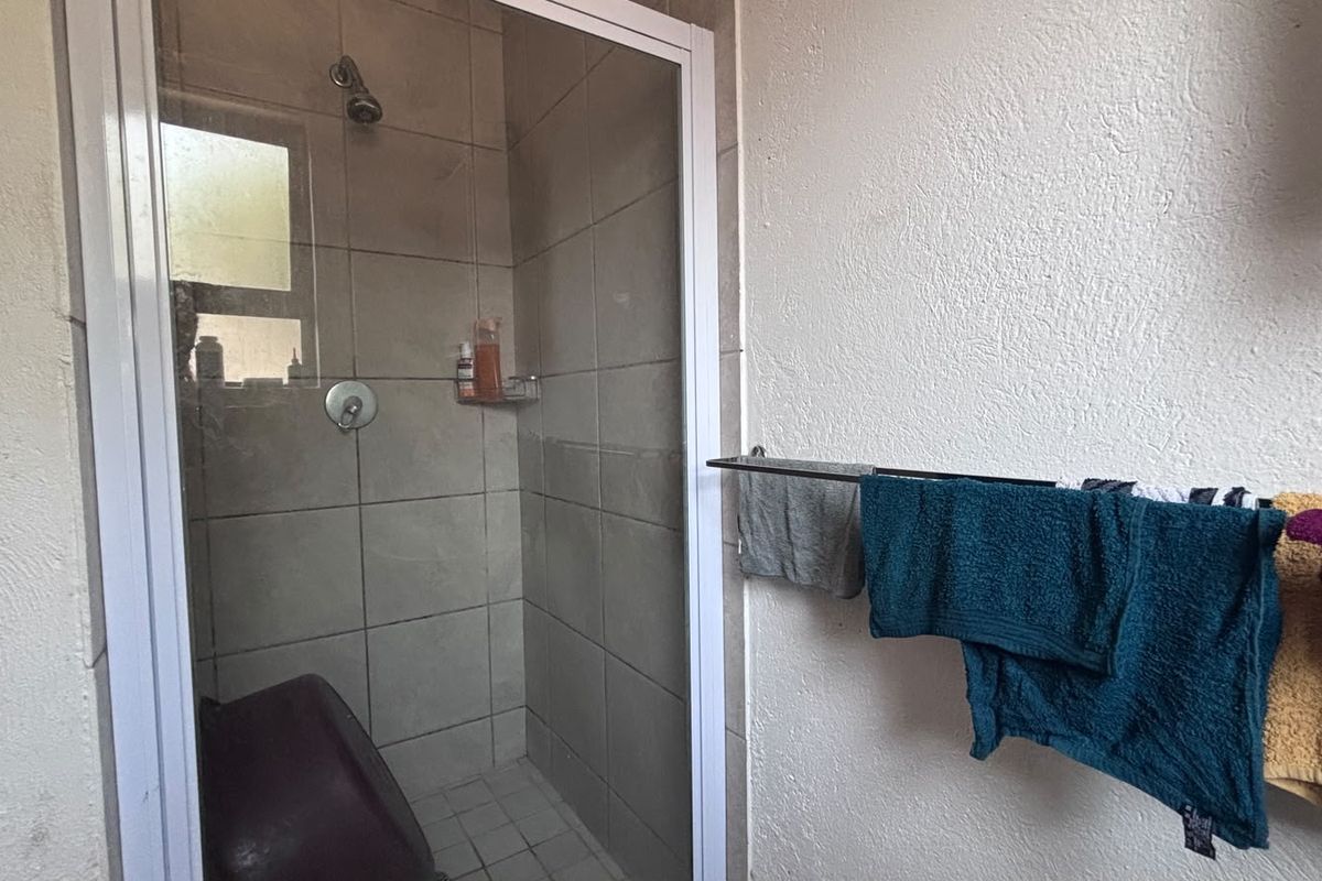 A functional bathroom featuring a tiled shower enclosure with a glass door and a wall-mounted towel rail.