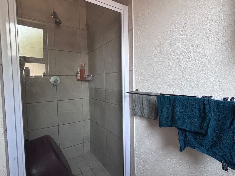 A functional bathroom featuring a tiled shower enclosure with a glass door and a wall-mounted towel rail.