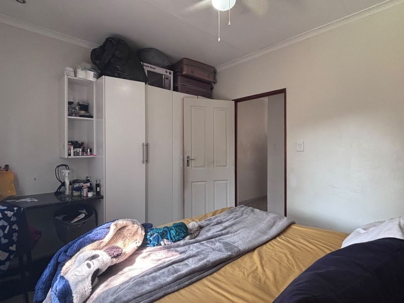A bedroom featuring a built-in wardrobe with integrated shelving and a ceiling fan.