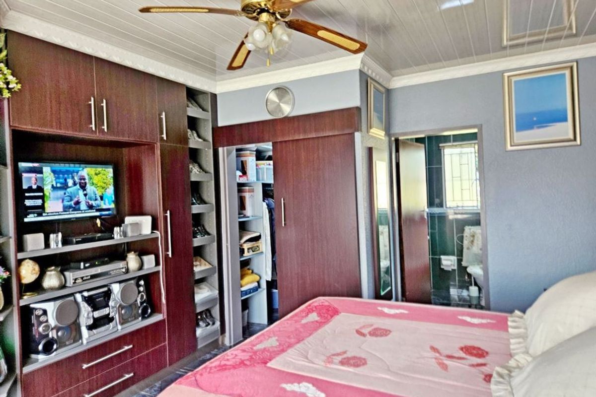 Bedroom featuring extensive built-in wooden cabinetry, a ceiling fan, and direct access to an en-suite bathroom.