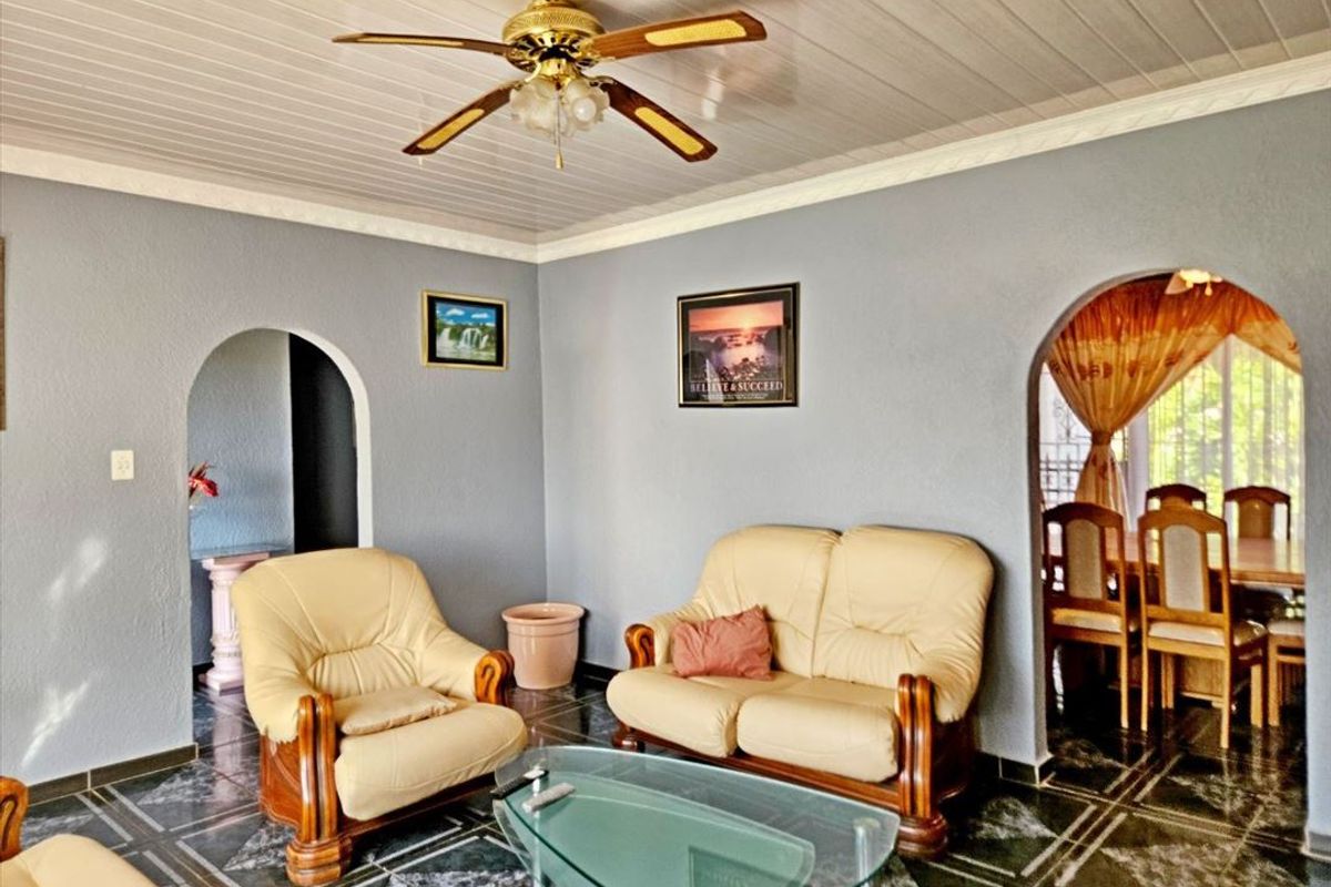 A living room featuring tiled flooring, a ceiling fan, and arched doorways leading to adjacent spaces, showcasing a traditional layout.