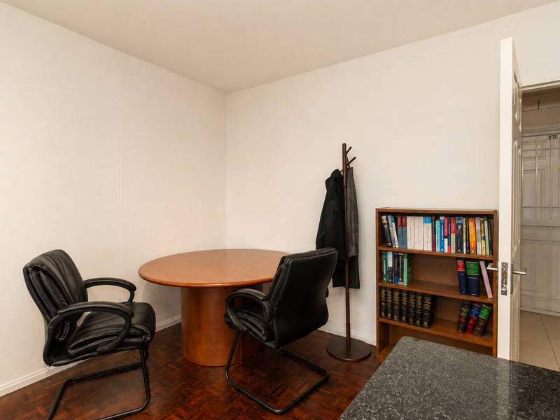 A functional office space featuring parquet flooring and a secure entrance gate, providing a quiet area suitable for a home workspace.