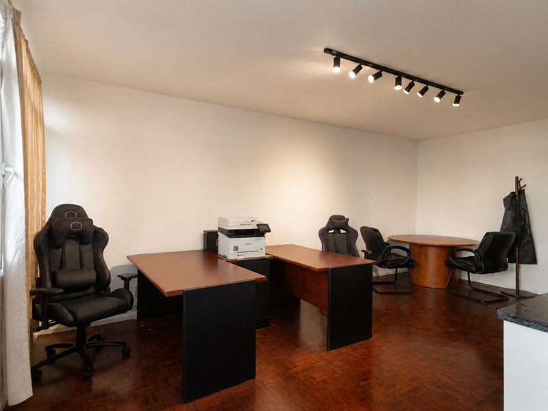 A functional office space featuring parquet flooring, track lighting, and large windows, providing a versatile area suitable for a home workspace.