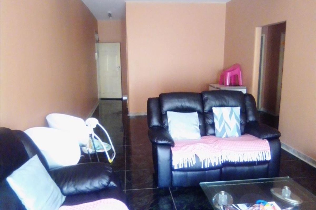 A living room area featuring dark tiled flooring and neutral wall paint, providing a functional space for relaxation.