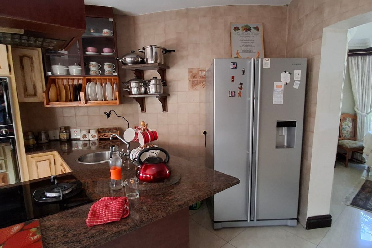 A functional kitchen featuring granite countertops, tiled backsplash, and built-in wooden cabinetry, with an open-plan layout leading to the dining area.
