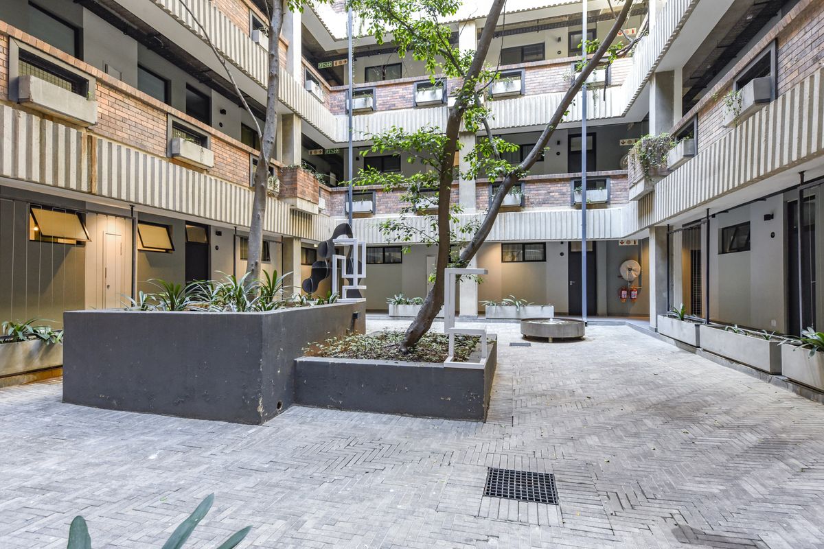 A central courtyard area within an apartment complex featuring brick paving, concrete planters, and multi-level building facades.