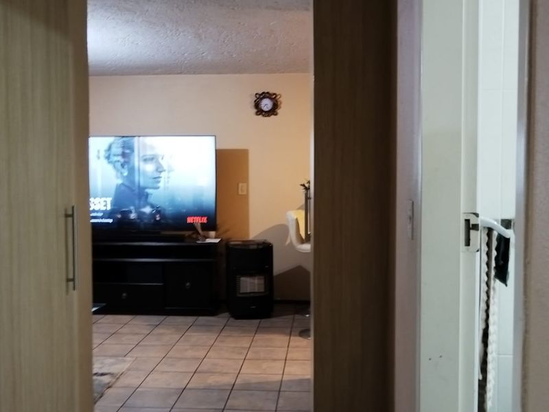A view from a hallway into a living area featuring ceramic floor tiles and built-in cabinetry.