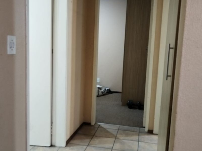 A functional hallway featuring tiled flooring and access to adjacent rooms, including a built-in cupboard for storage.