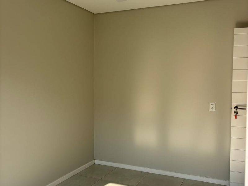 A bright, empty bedroom featuring neutral wall tones, tiled flooring, a modern ceiling fan, and recessed lighting.