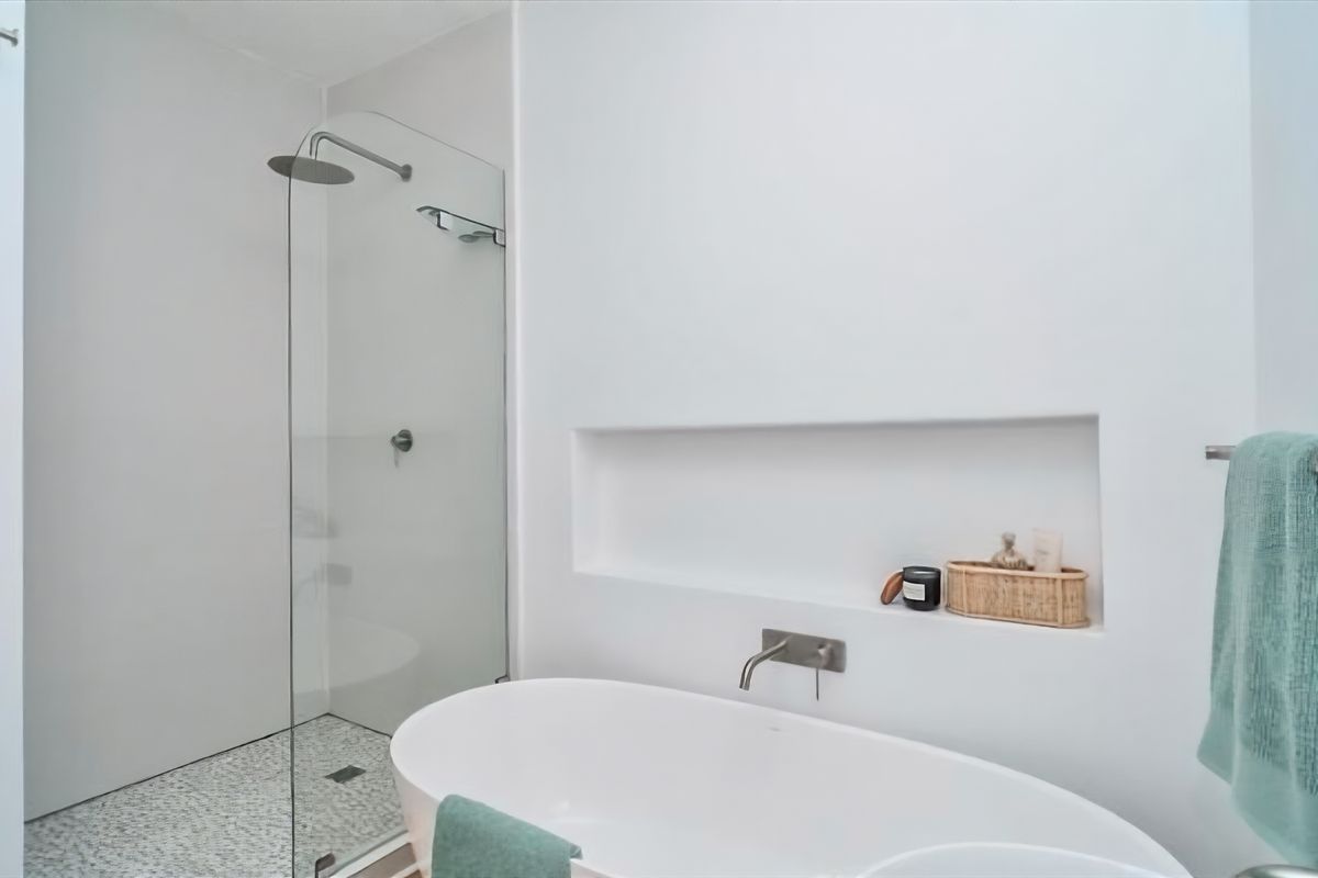 Modern bathroom featuring a sleek freestanding bathtub, a walk-in shower with a glass screen, and a convenient recessed wall niche for storage.