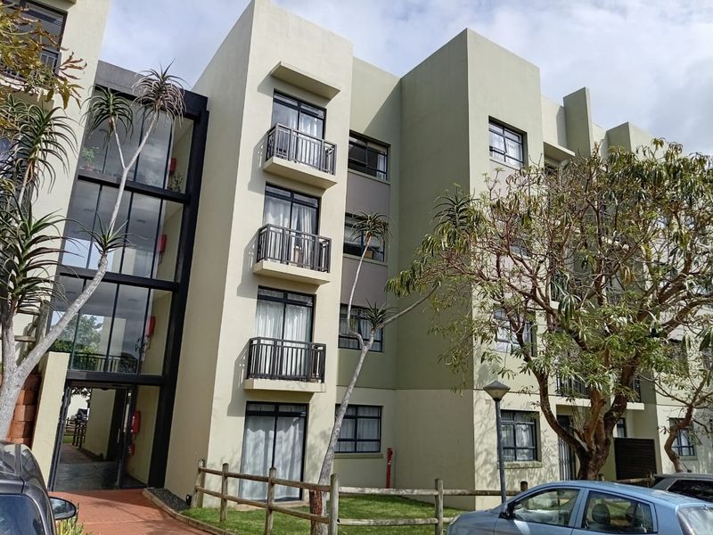 A multi-story apartment building facade featuring modern architectural lines, private balconies with metal railings, and large sliding glass doors.