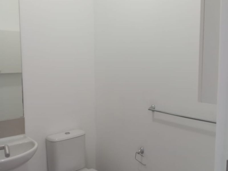 A clean and minimalist guest bathroom featuring a modern toilet, wall-mounted basin, and essential fixtures in a neutral white finish.