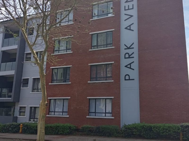 Exterior view of the Park Avenue apartment building featuring a brick facade and paved street-level access.