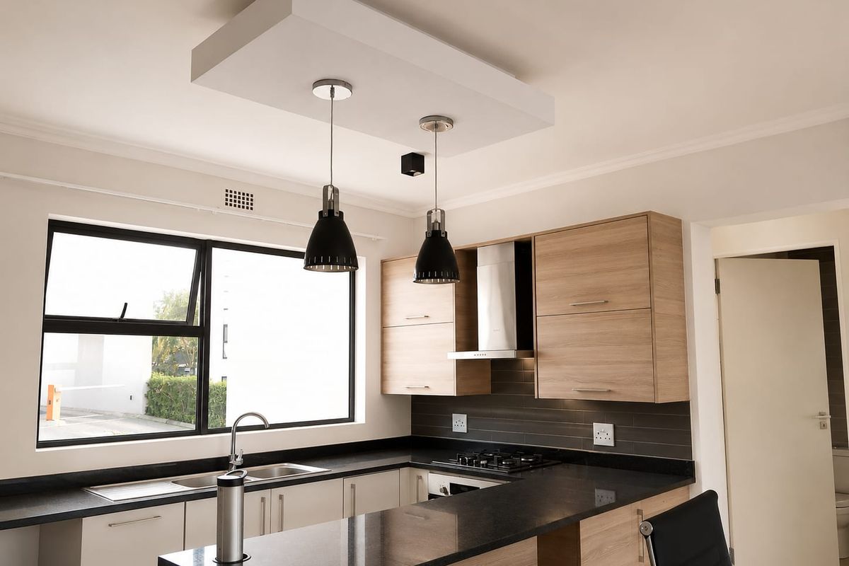Modern kitchen featuring light wood cabinetry, dark granite countertops, stainless steel appliances, and a functional layout with a breakfast bar.
