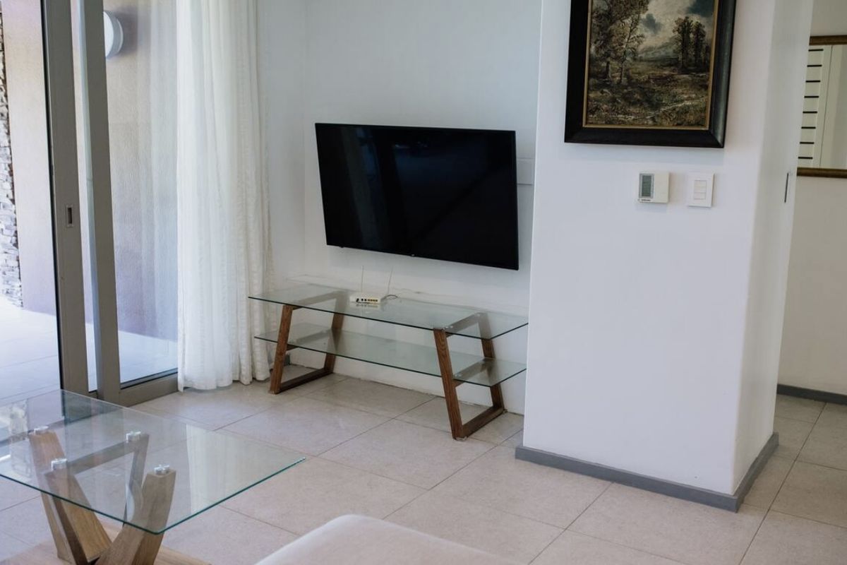 A bright living room area featuring tiled flooring and a large sliding glass door providing access to an outdoor space.