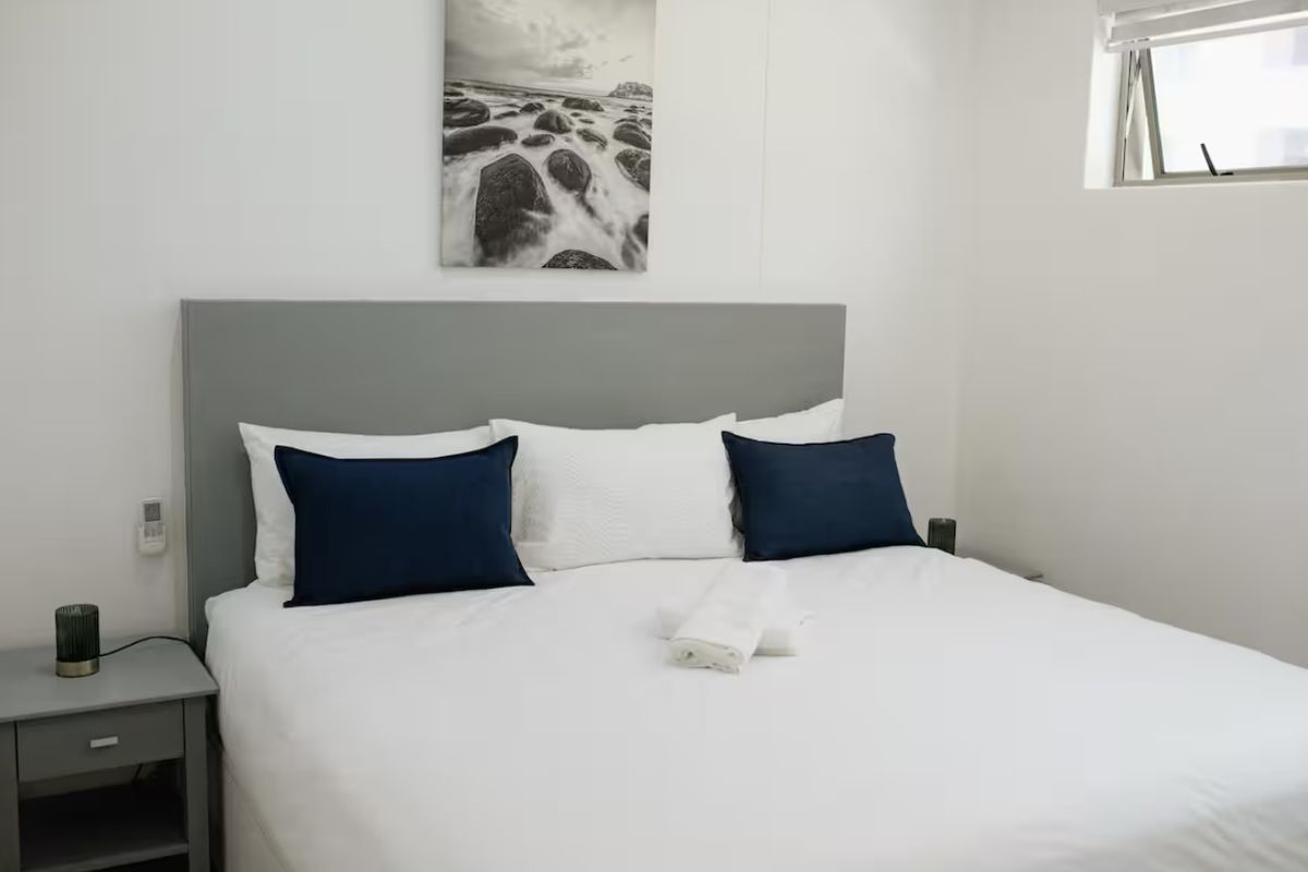 A clean and well-maintained bedroom featuring neutral walls and an awning window, providing a bright and comfortable sleeping space.