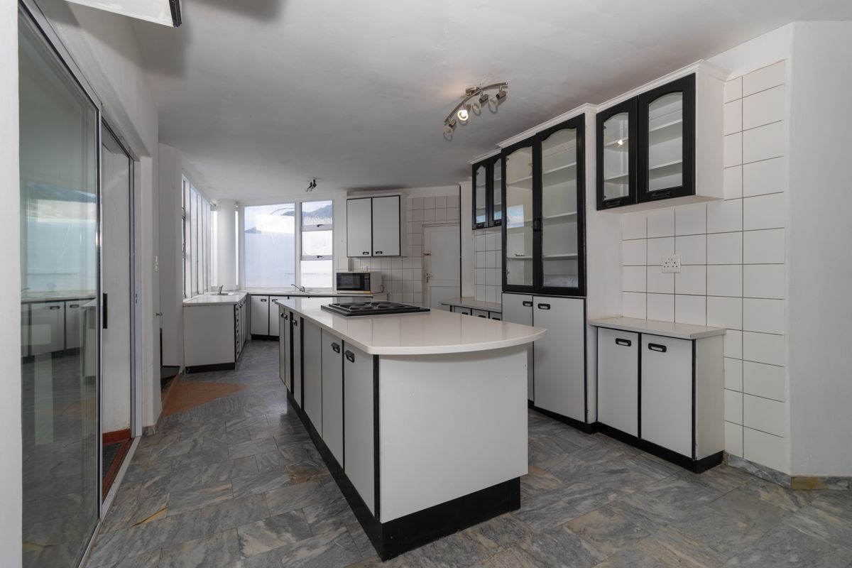 Spacious kitchen featuring a central island, ample built-in cabinetry, stone countertops, and tiled backsplash, offering a functional layout ready for modernization.