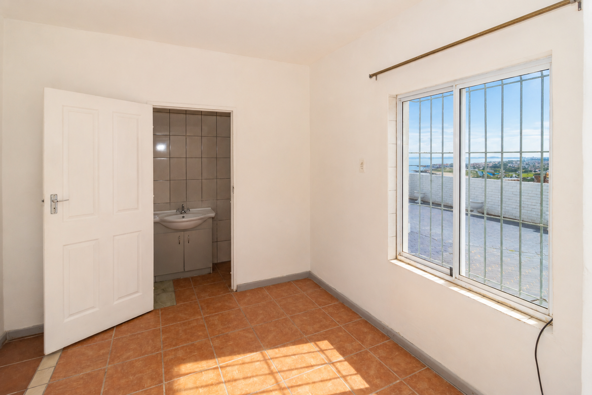 An empty bedroom featuring ceramic floor tiles, a window with security bars, and direct access to an en-suite bathroom.
