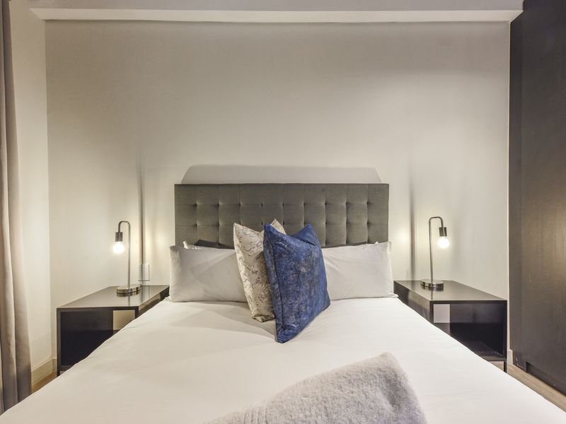 A well-maintained bedroom featuring neutral walls, laminate flooring, and a built-in wardrobe, providing a clean and functional living space.