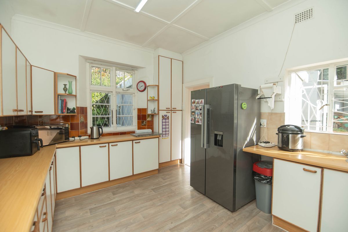 A functional kitchen featuring laminate cabinetry, timber-look countertops, tiled splashbacks, and vinyl flooring, offering a practical layout with ample natural light.
