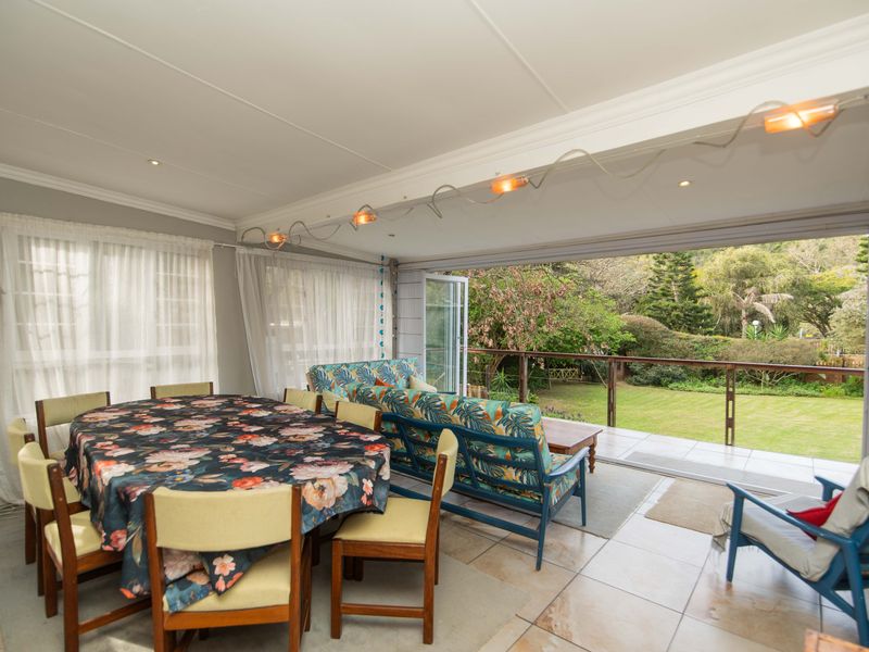 Spacious open-plan living and dining area featuring large folding glass doors that open onto a garden-facing deck.