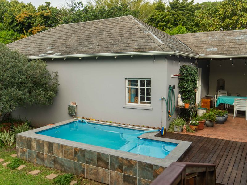 Outdoor area featuring a raised swimming pool with tiled surround, adjacent timber decking, and a covered patio space.