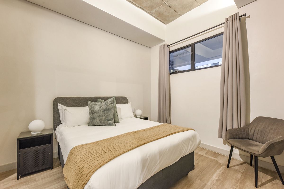 A modern, well-maintained bedroom featuring recessed ceiling detail with cove lighting, laminate flooring, and a horizontal window providing natural light.
