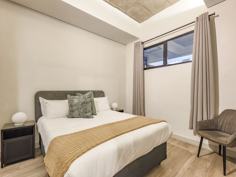 A modern, well-maintained bedroom featuring recessed ceiling detail with cove lighting, laminate flooring, and a horizontal window providing natural light.