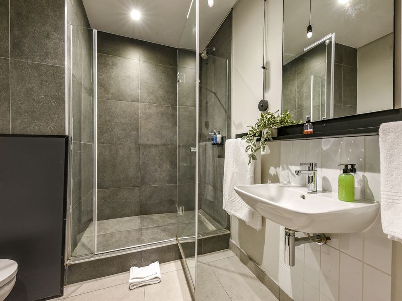 Modern bathroom featuring a walk-in shower with glass screen, wall-mounted basin, and large vanity mirror with contemporary finishes.