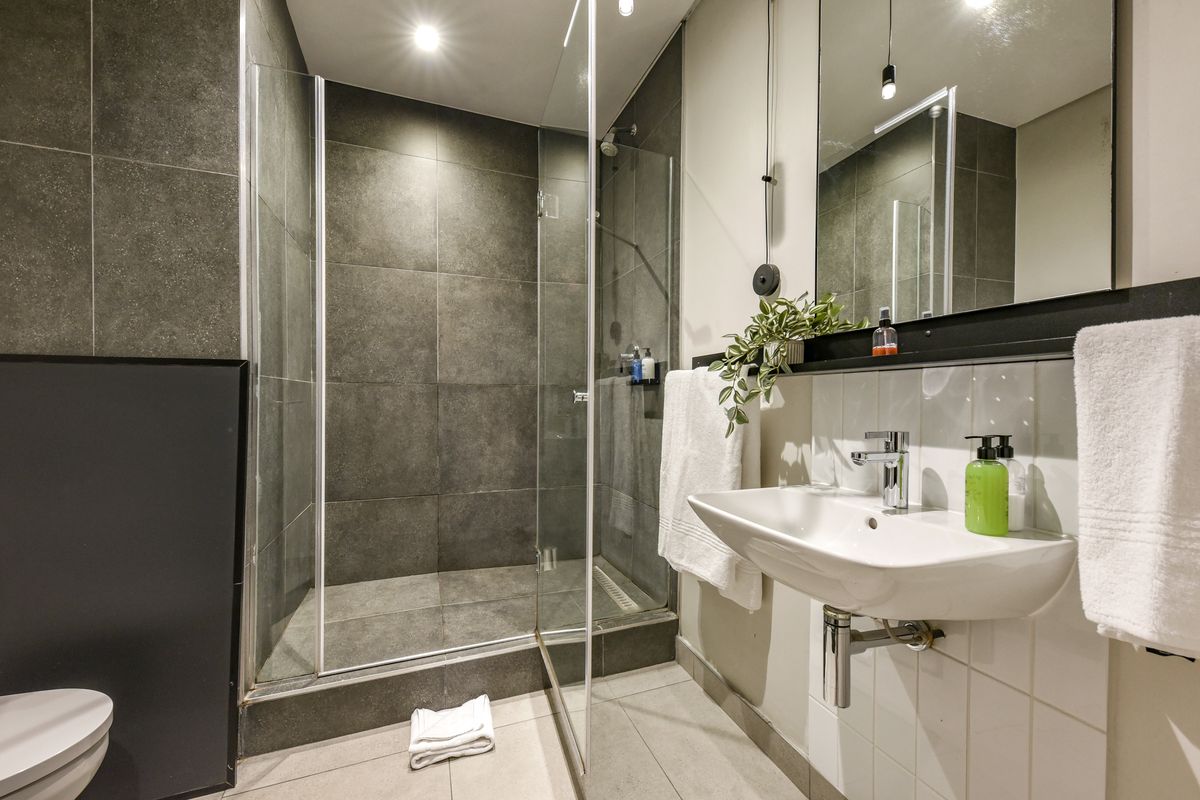 Modern bathroom featuring a walk-in shower with glass screen, wall-mounted basin, and large vanity mirror with contemporary finishes.