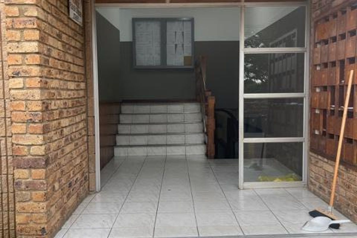 The apartment building entrance features a brick facade, tiled steps, a timber-lined ceiling, and a bank of mailboxes in the foyer area.