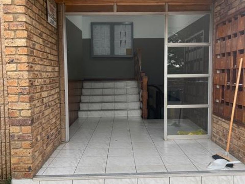 The apartment building entrance features a brick facade, tiled steps, a timber-lined ceiling, and a bank of mailboxes in the foyer area.