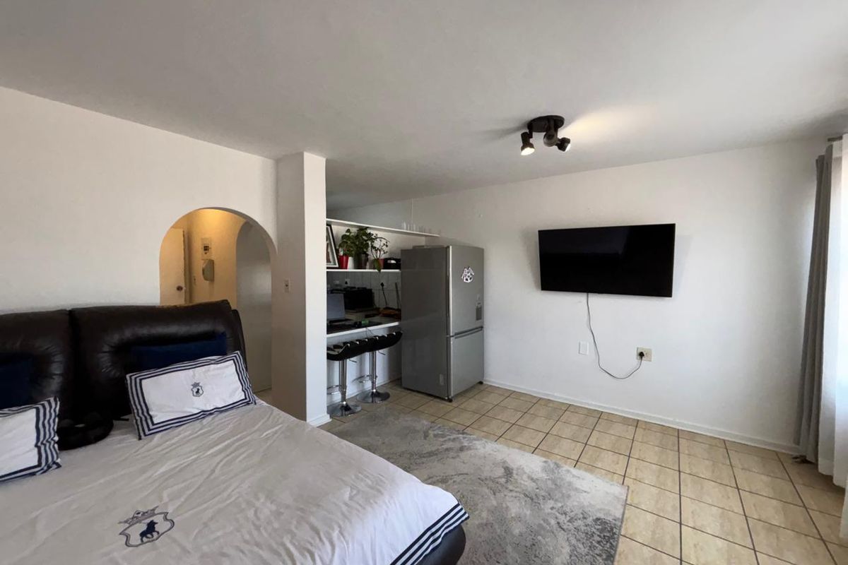 A bedroom featuring tiled flooring, an arched entryway, and a built-in breakfast bar area with overhead spotlighting.