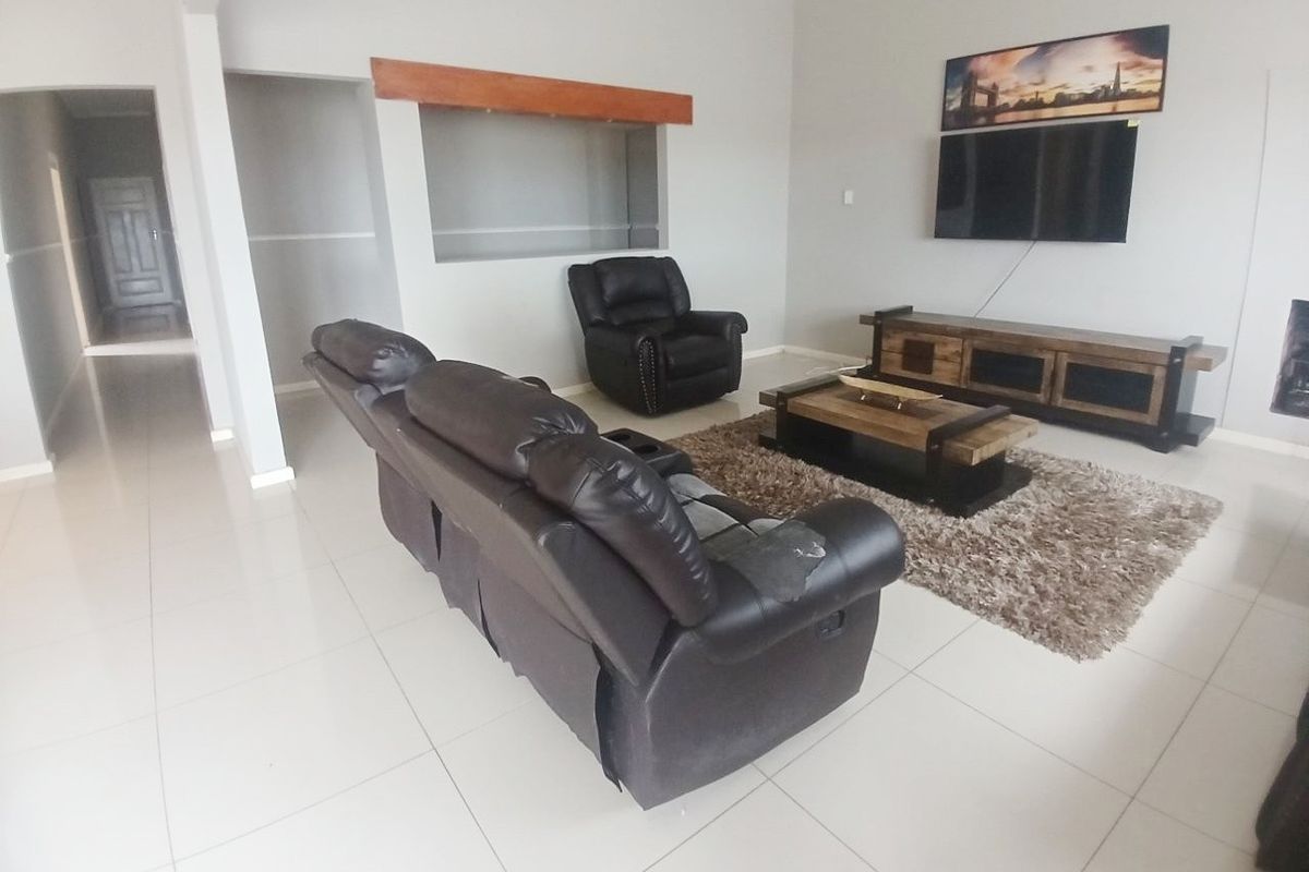 A spacious living room featuring neutral tiled flooring and a built-in wall niche, offering a clean and functional layout for relaxation.
