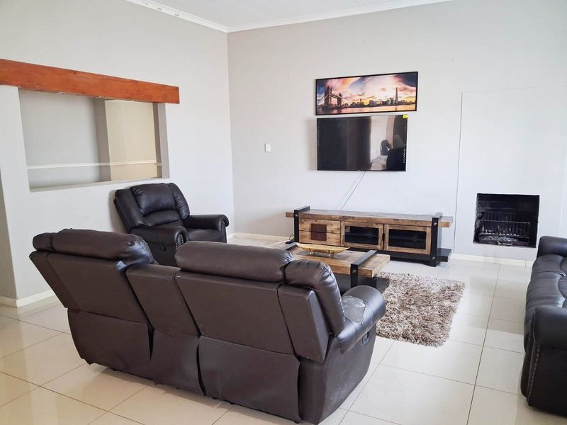 A living room featuring tiled flooring, a built-in fireplace, and a pass-through window connecting to an adjacent space.