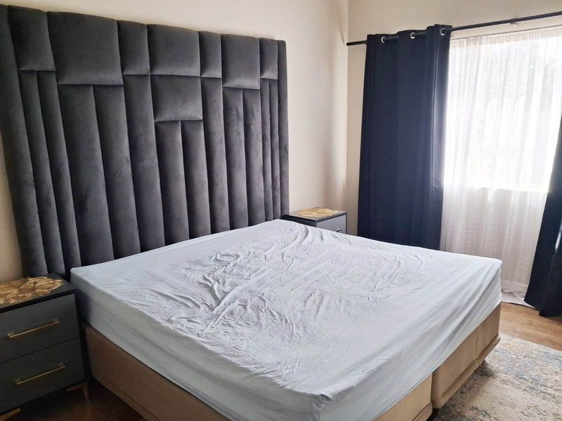 A well-maintained bedroom featuring a large upholstered headboard and window treatments.
